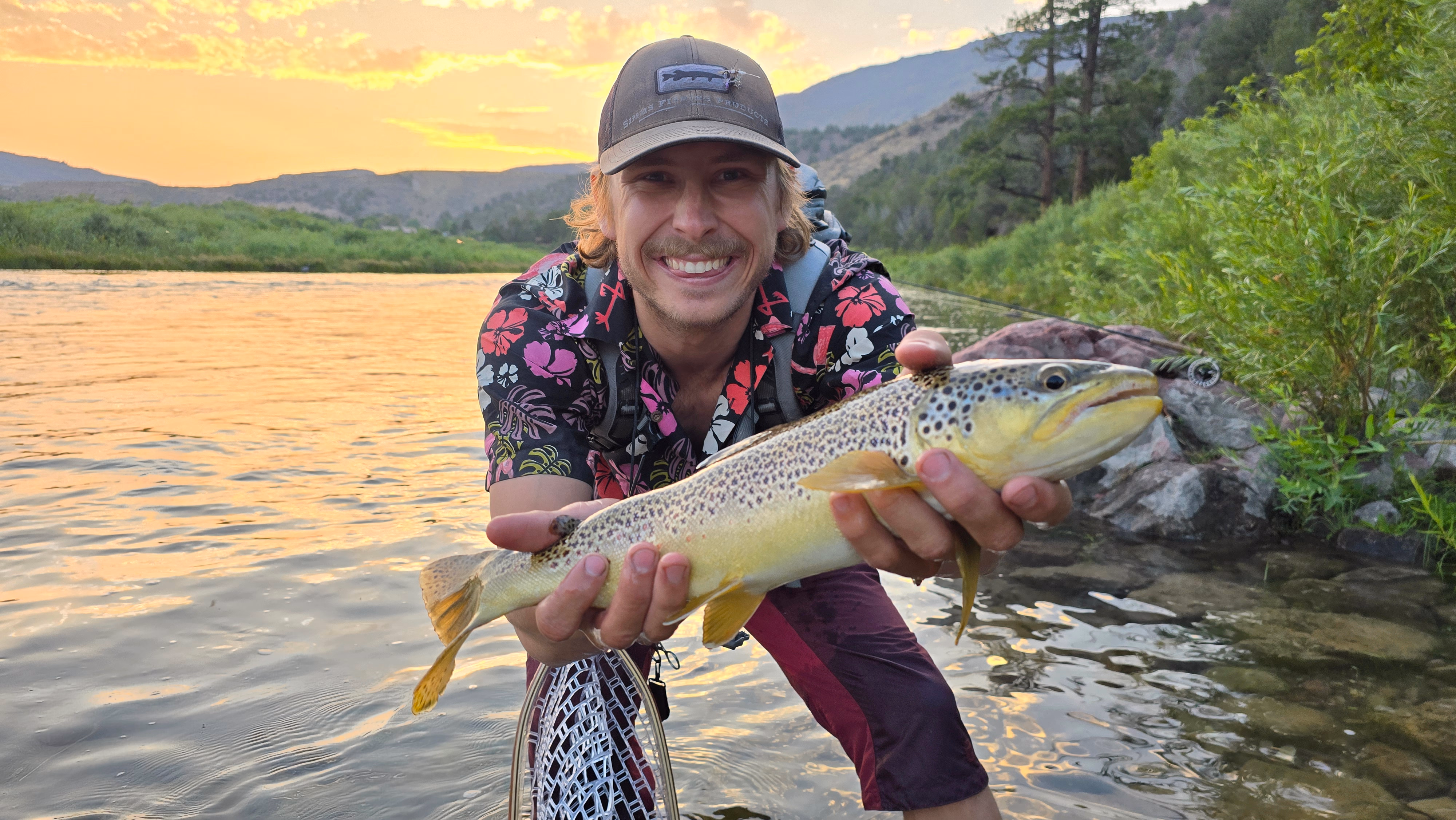 Owen, holding a brown trout at sunset on a river, somewhere drier than Bellingham.